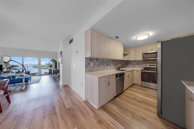 kitchen with open shelves, light countertops, decorative backsplash, appliances with stainless steel finishes, and a sink