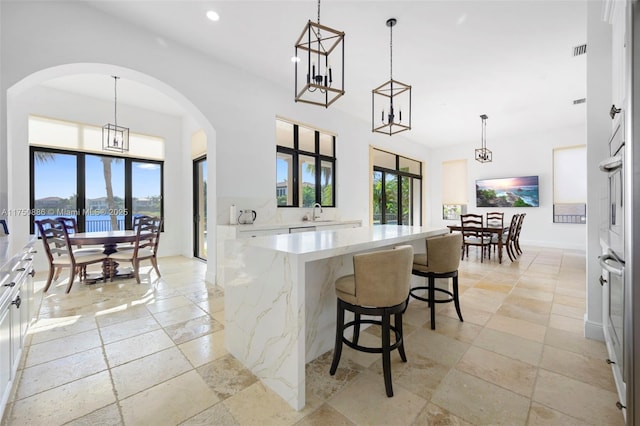 kitchen featuring light stone counters, stone tile floors, a kitchen island, visible vents, and white cabinets