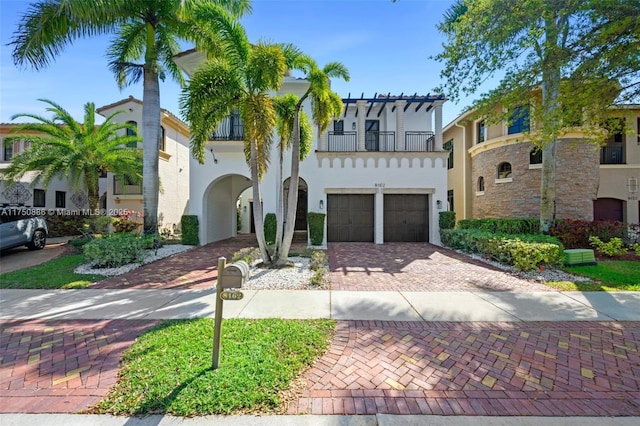 mediterranean / spanish house featuring a balcony, a garage, decorative driveway, and stucco siding