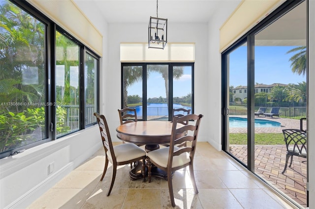 sunroom / solarium with an inviting chandelier, a water view, and a healthy amount of sunlight