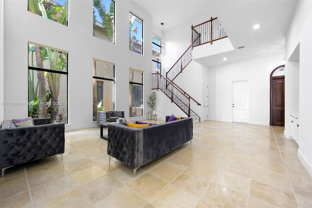 living room featuring baseboards, visible vents, a towering ceiling, stairway, and recessed lighting