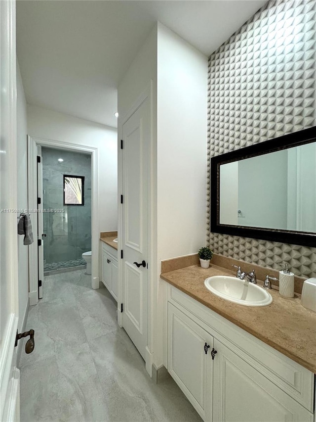 bathroom with toilet, a stall shower, vanity, and baseboards