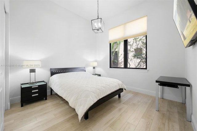 bedroom with a chandelier, wood finished floors, and baseboards