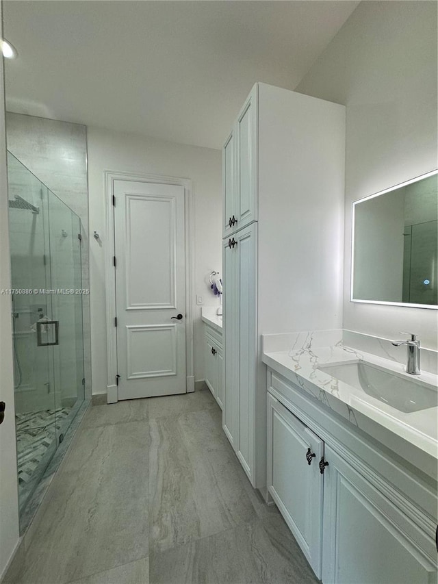 bathroom with marble finish floor, two vanities, a sink, and a shower stall