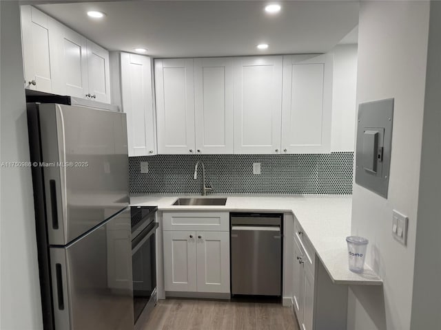 kitchen with light countertops, appliances with stainless steel finishes, a sink, and white cabinetry