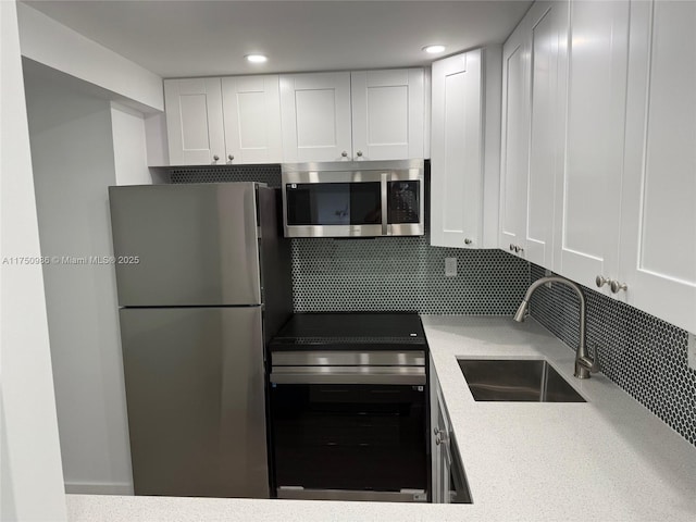 kitchen with stainless steel appliances, light countertops, decorative backsplash, white cabinets, and a sink