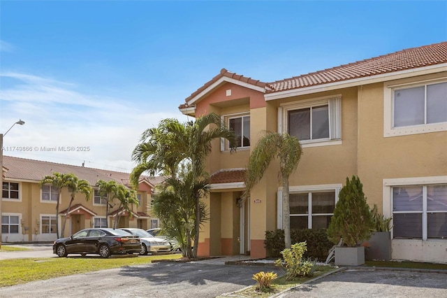 townhome / multi-family property featuring a tile roof and stucco siding