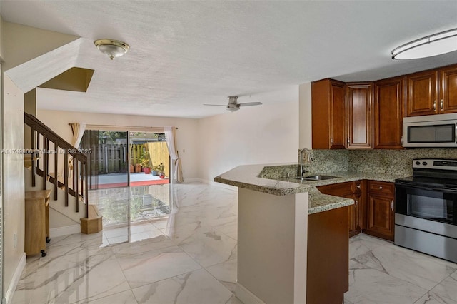 kitchen with a peninsula, a sink, marble finish floor, appliances with stainless steel finishes, and brown cabinetry