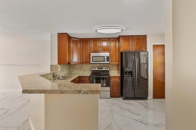 kitchen featuring marble finish floor, appliances with stainless steel finishes, a sink, light stone countertops, and a peninsula