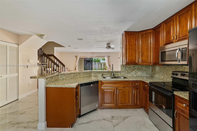 kitchen featuring light stone counters, marble finish floor, stainless steel appliances, a sink, and a peninsula