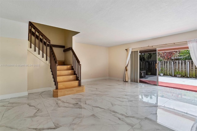 interior space featuring marble finish floor, a textured ceiling, baseboards, and stairs