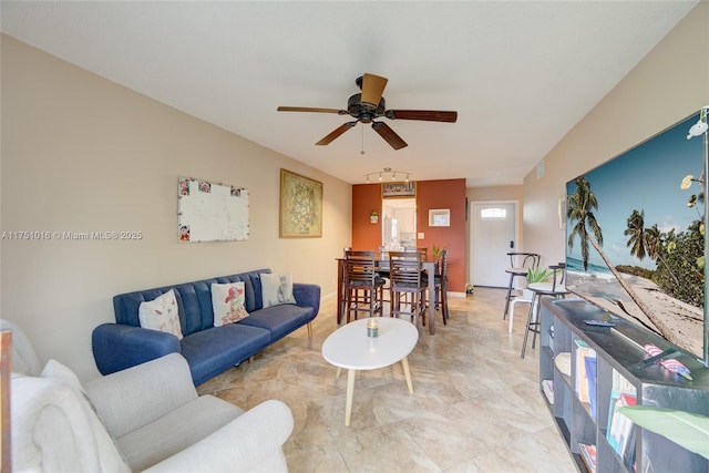 living area featuring ceiling fan and baseboards