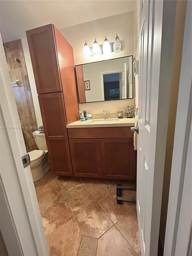 full bath with tiled shower, vanity, and toilet