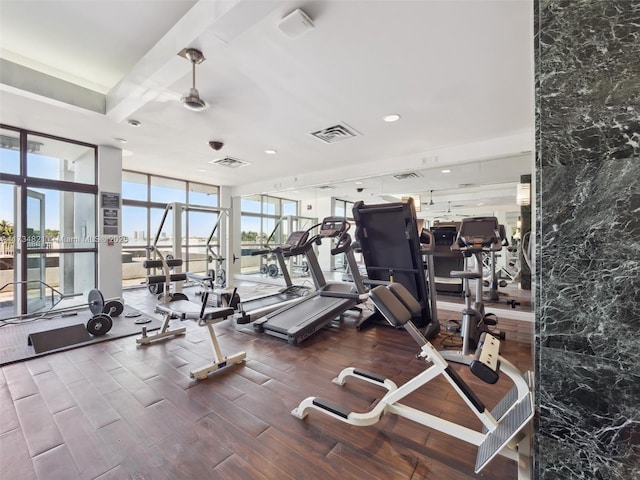 exercise room featuring a ceiling fan, a wall of windows, wood finished floors, and visible vents