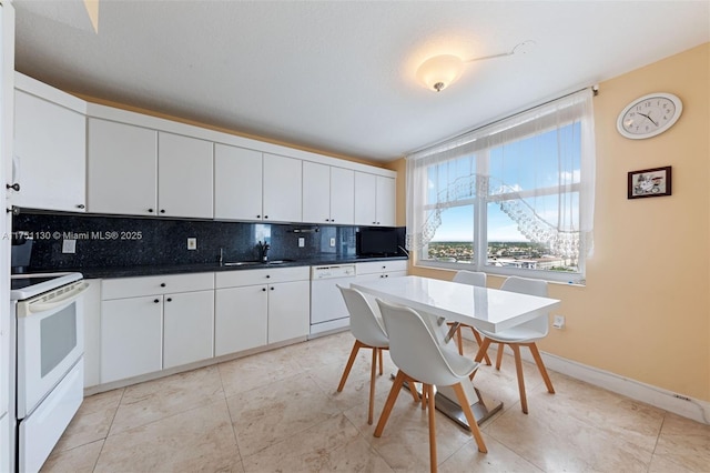 kitchen with dark countertops, white appliances, tasteful backsplash, and a sink