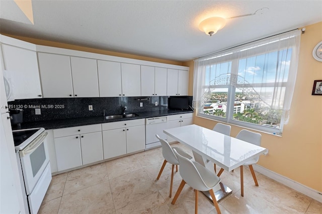 kitchen with white appliances, decorative backsplash, dark countertops, white cabinetry, and a sink