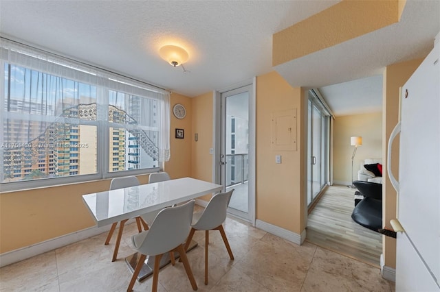 dining space featuring a textured ceiling, light tile patterned flooring, and baseboards