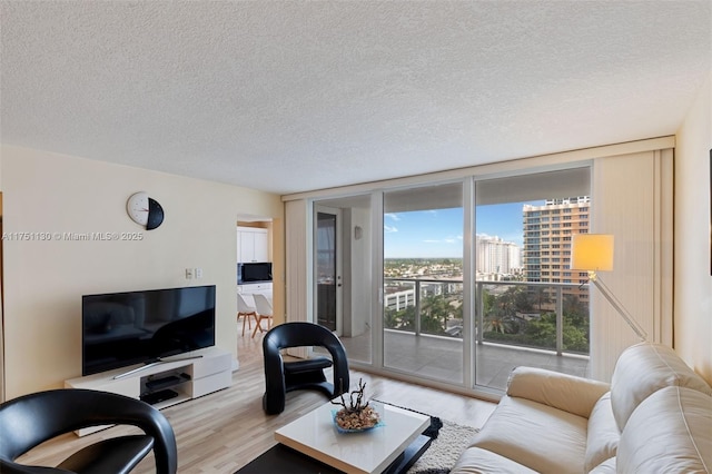 living area featuring expansive windows, a textured ceiling, wood finished floors, and a city view