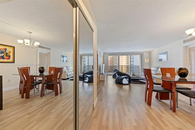 dining space featuring light wood-style floors, a notable chandelier, baseboards, and a textured ceiling