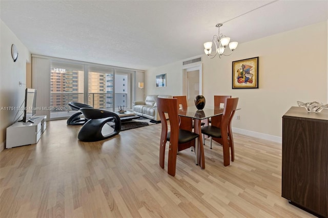 dining area featuring visible vents, baseboards, a textured ceiling, light wood-type flooring, and floor to ceiling windows