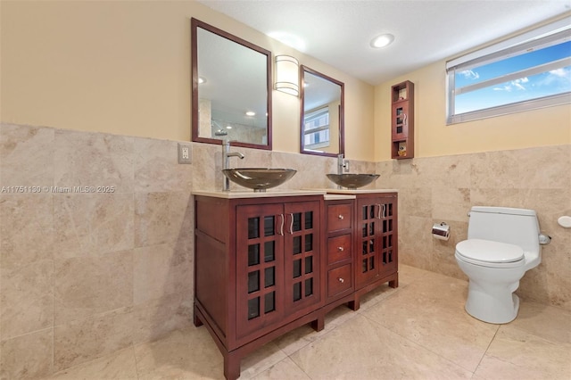 full bath featuring toilet, tile walls, and a sink