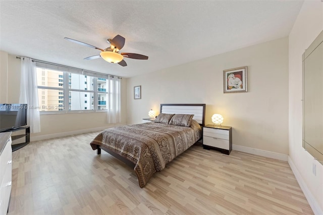 bedroom featuring light wood-style flooring, baseboards, ceiling fan, and a textured ceiling