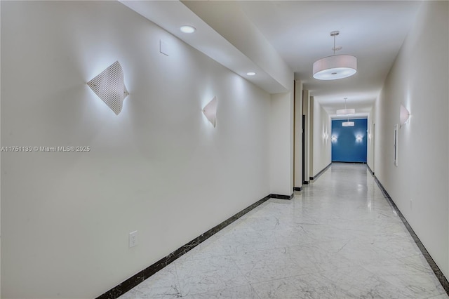 hall with recessed lighting, marble finish floor, and baseboards