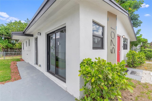 view of side of home with fence and stucco siding