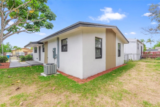 view of property exterior with a yard, stucco siding, central air condition unit, a patio area, and fence