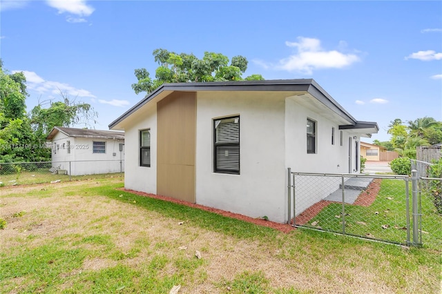 view of side of property with a lawn, fence, and stucco siding