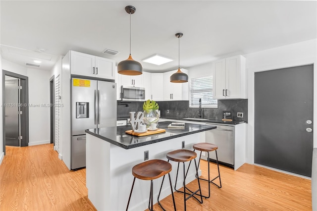 kitchen featuring stainless steel appliances, dark countertops, white cabinets, and visible vents