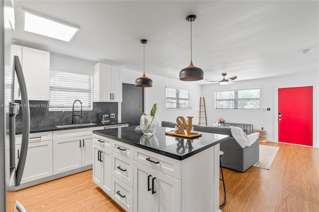 kitchen with dark countertops, a sink, decorative light fixtures, and white cabinets