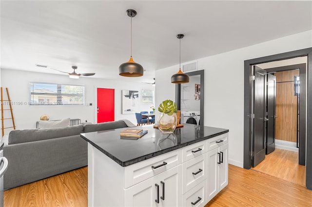 kitchen featuring visible vents, open floor plan, light wood-type flooring, white cabinetry, and pendant lighting