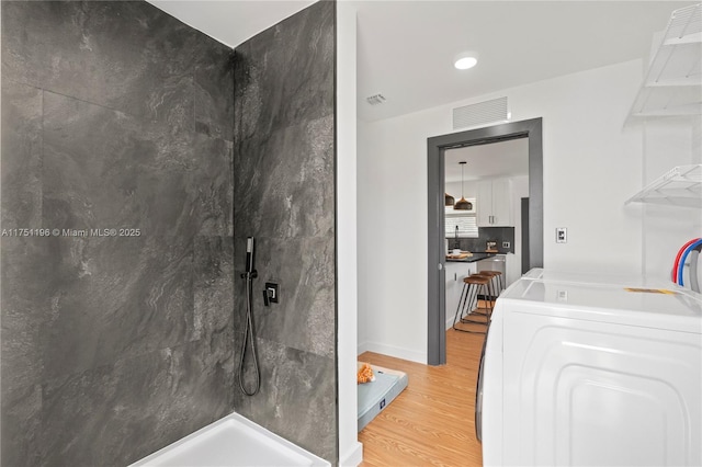 bathroom with visible vents, decorative backsplash, wood finished floors, baseboards, and walk in shower