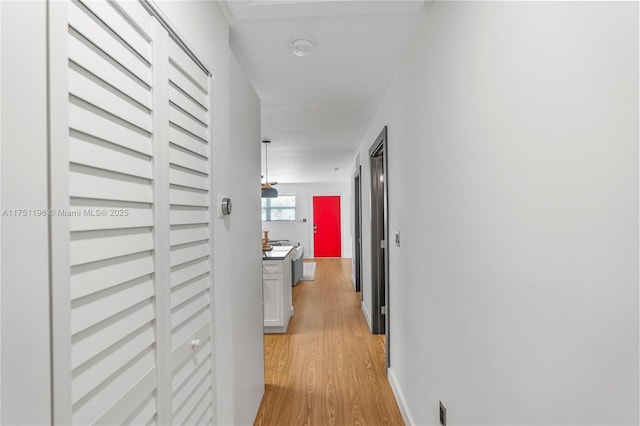 hall with light wood-style floors and baseboards