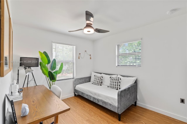 interior space featuring a ceiling fan, multiple windows, baseboards, and wood finished floors