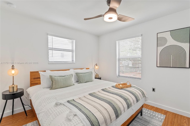 bedroom featuring ceiling fan, light wood-style flooring, and baseboards