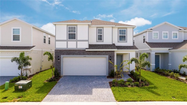 view of front of property with an attached garage, roof with shingles, decorative driveway, and a front yard