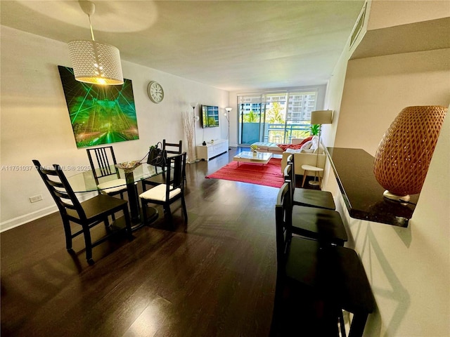 dining space featuring dark wood-type flooring and baseboards