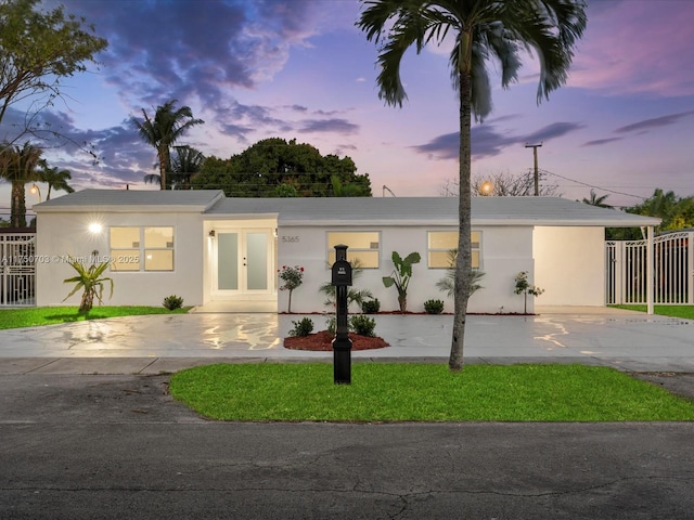 view of front facade with fence, french doors, concrete driveway, and stucco siding