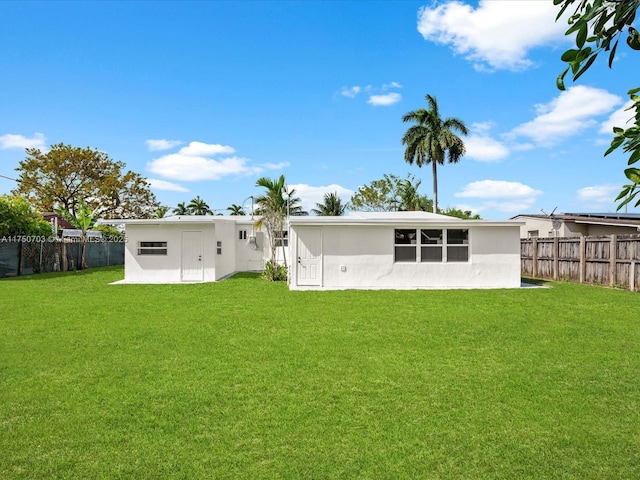 back of house featuring a lawn and fence