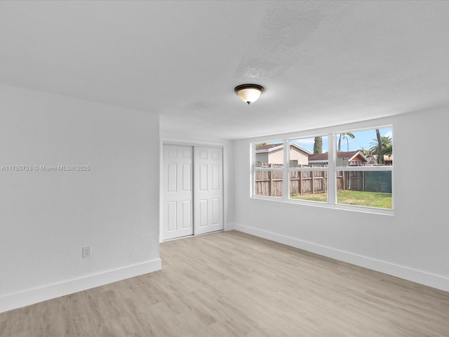 interior space with a textured ceiling, light wood finished floors, a closet, and baseboards