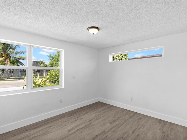 spare room featuring a textured ceiling, baseboards, and wood finished floors