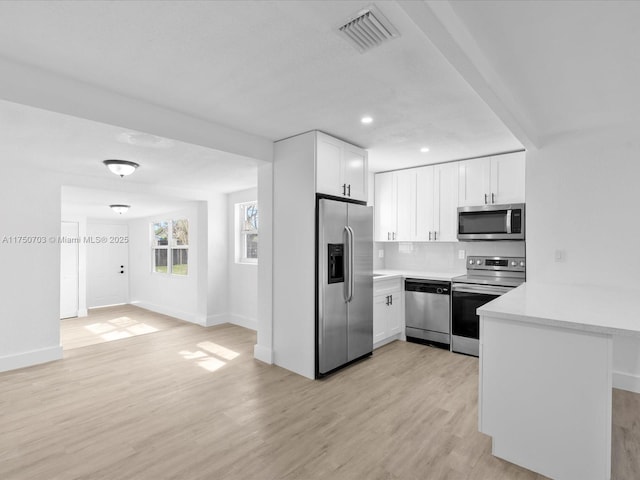 kitchen featuring stainless steel appliances, a peninsula, visible vents, white cabinetry, and light countertops