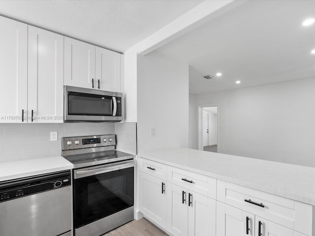 kitchen featuring white cabinetry, tasteful backsplash, appliances with stainless steel finishes, and light countertops