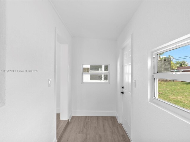 hallway featuring light wood finished floors and baseboards