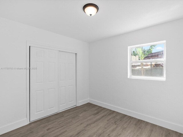 unfurnished bedroom featuring a closet, baseboards, and wood finished floors