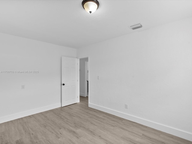 spare room with visible vents, baseboards, and wood finished floors