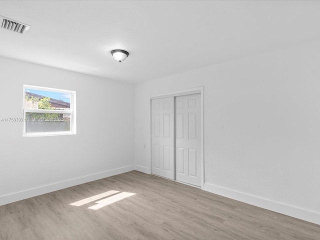 unfurnished bedroom with visible vents, a closet, baseboards, and wood finished floors