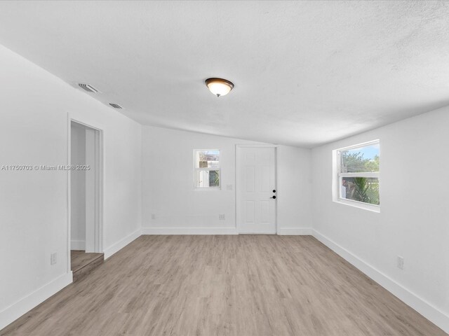 unfurnished room with plenty of natural light, light wood-style flooring, and baseboards